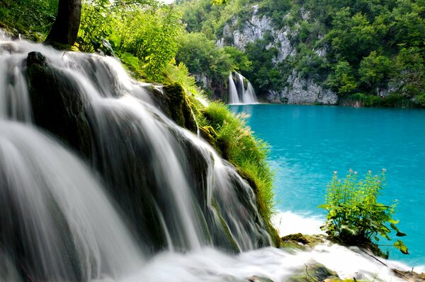 Cascada de montaña que desemboca en el lago azul