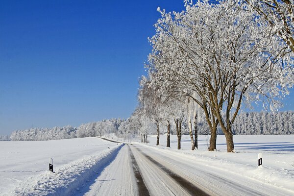 Schneegestöberte Straße am Winterwald