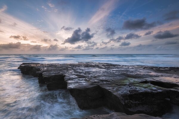 The blue waves of the surf beat against the rocky shore