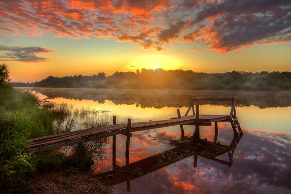 Río de la mañana con un puente en la niebla