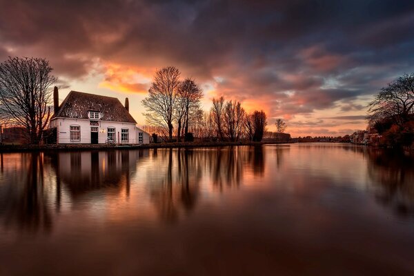 The house on the river bank is reflected in the water