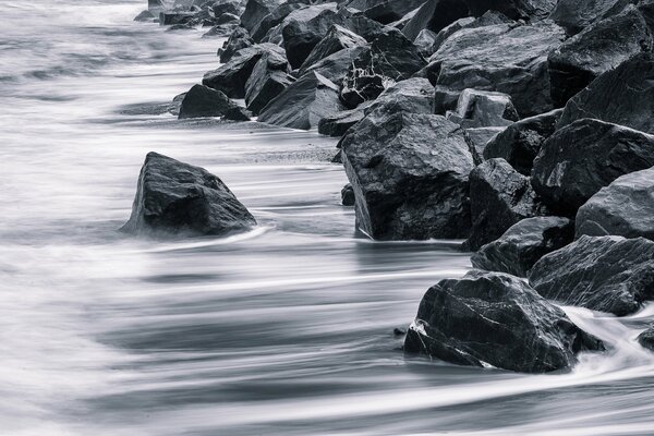 Le rocce muscolose sorvegliano la riva che accarezza delicatamente il surf