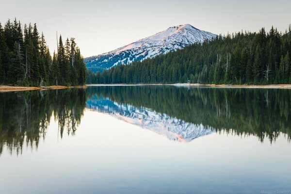 Reflection of a mountain peak in the water forest shore