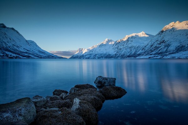 Paisaje de un lago de invierno con una orilla rocosa