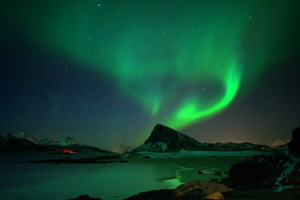 Aurora boreal por la noche en las montañas cerca del lago