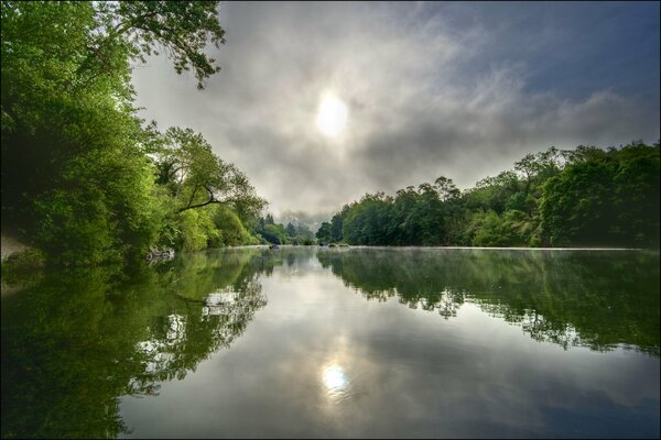 Il sole e gli alberi si riflettono nel fiume