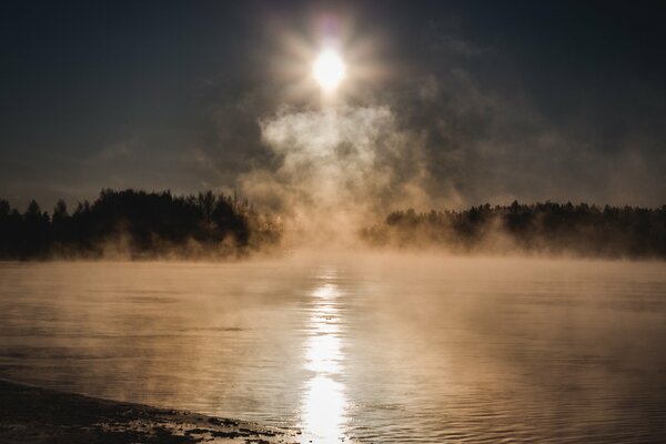Wschód słońca nad jeziorem w zimnej mgle