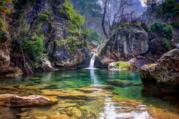 Landscape lake among rocks with waterfall