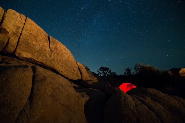 Carpa roja entre las montañas por la noche