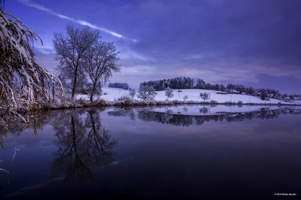 View of the lake and a snowy hillock with trees