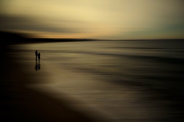 Dos siluetas en la orilla del mar