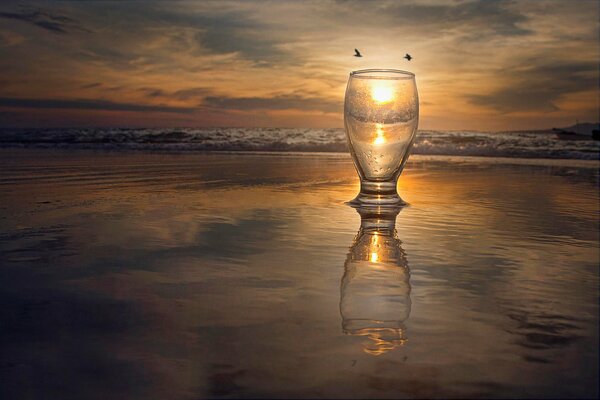 Отражение солнца в стакане на фоне моря