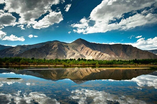 Majestic mountains and clouds are reflected in the mirror surface of the lake