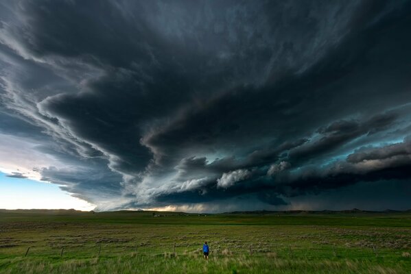 A man in a field under a stormy dark sky