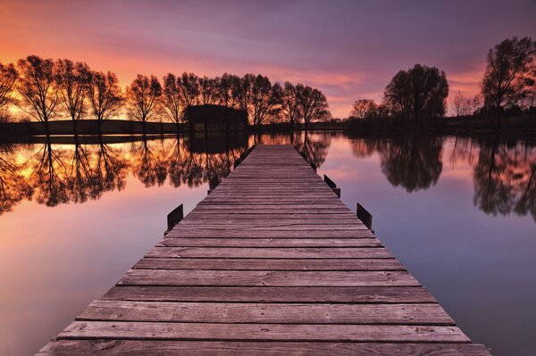 Coucher de soleil violet illumine la jetée dans le lac