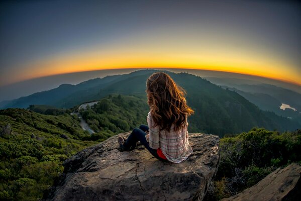 A girl admires the sunset from a great height