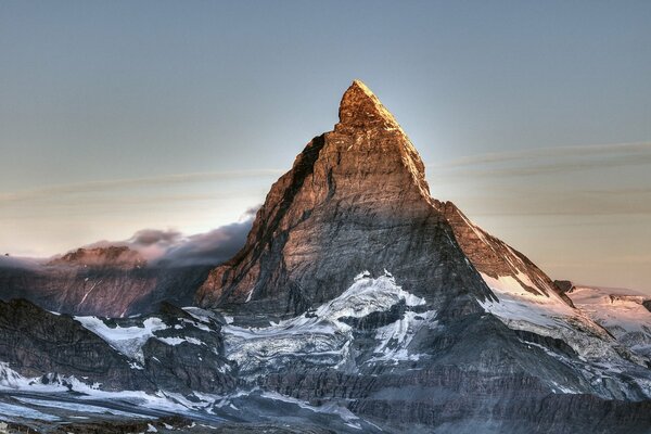 A snow-capped peak pierces the sky with a sharp spire