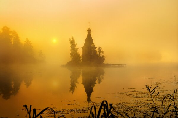 Die Kirche ist in Nebel über dem Wasser gehüllt