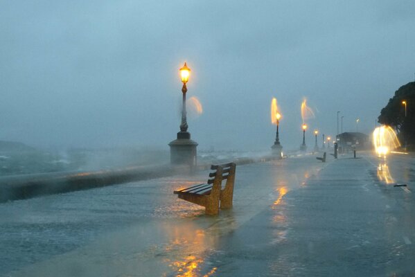 A lonely bench on the embankment in a storm by the light of lanterns