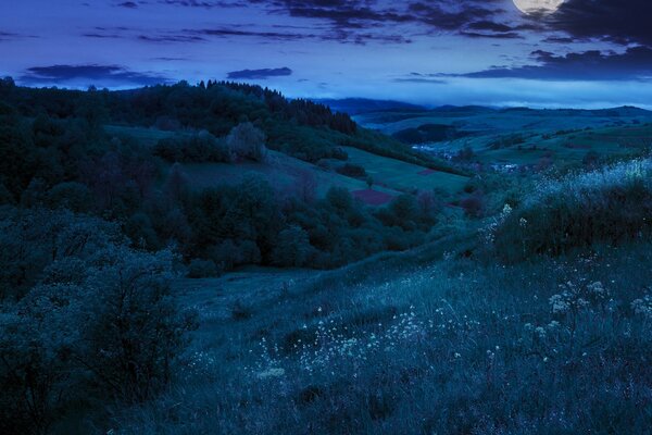 Luna piena sopra la valle notturna con le colline