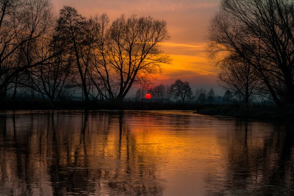 Le coucher de soleil de feu se reflète dans la rivière