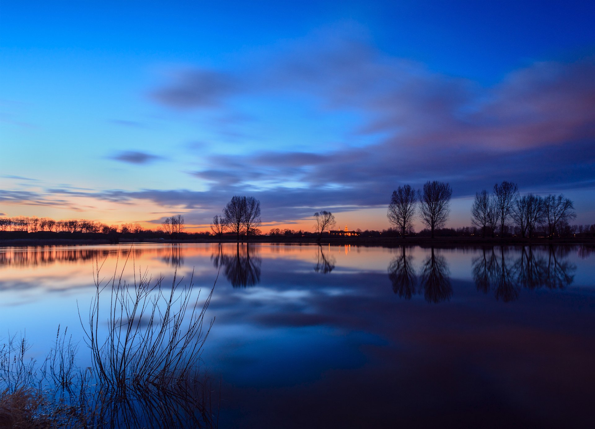 paesi bassi fiume acqua superficie liscia riva alberi sera tramonto cielo nuvole riflessione