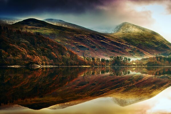 Sunset. Reflection of hills in the surface of the lake