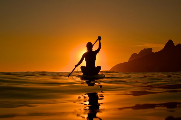 Silhouette d une jeune fille dans les rayons du coucher du soleil sur un kayak