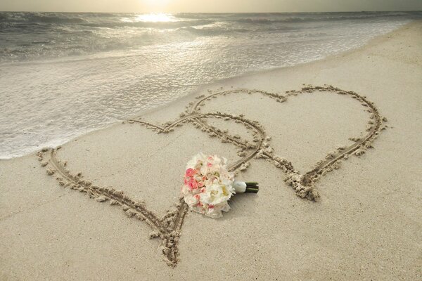 Two hearts painted on a sandy beach