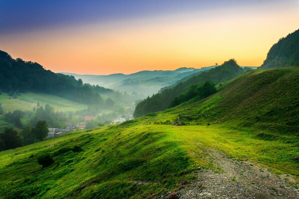 A green glade in the mountains against the background of sunset