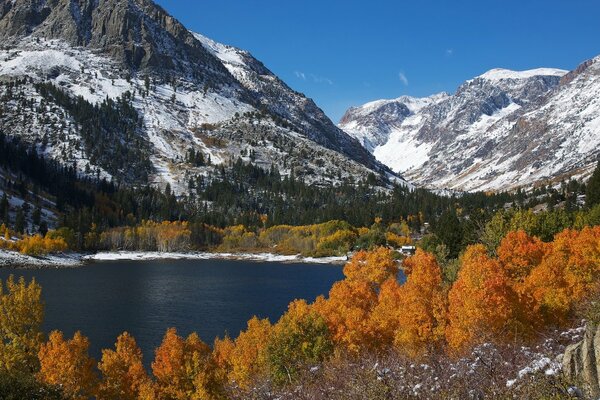 Lac parmi les montagnes enneigées et les arbres jaunes