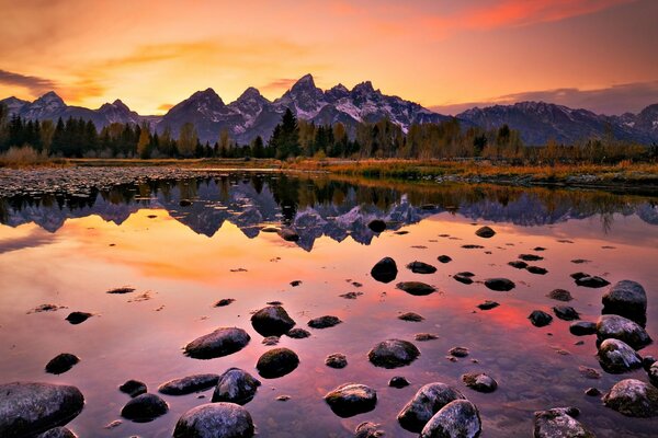 Pierres dans l eau sur fond de montagnes au soleil couchant