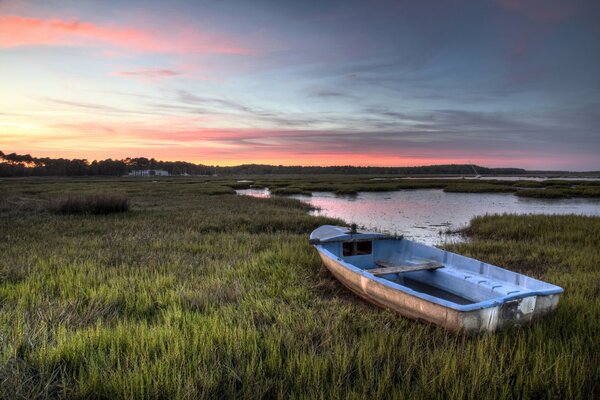 Barco junto al lago y puesta de sol rosa