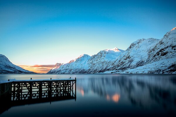 Molo sul lago e montagne coperte di neve