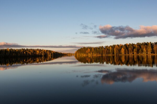 Clouds are displayed on a wide river in the forest