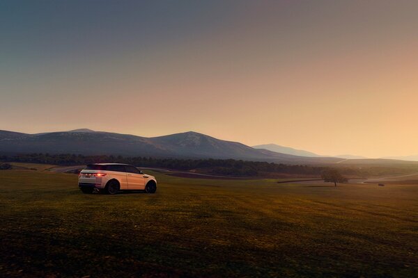 A car on a hill in the middle of a field