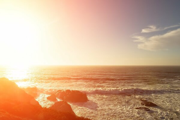 Le onde infuriate che si riflettono dal sole battono contro le rocce