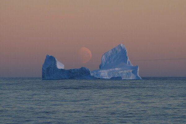 Góra lodowa w Morzu Rossa na tle księżyca