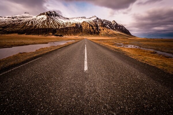 Route déserte menant aux montagnes enneigées