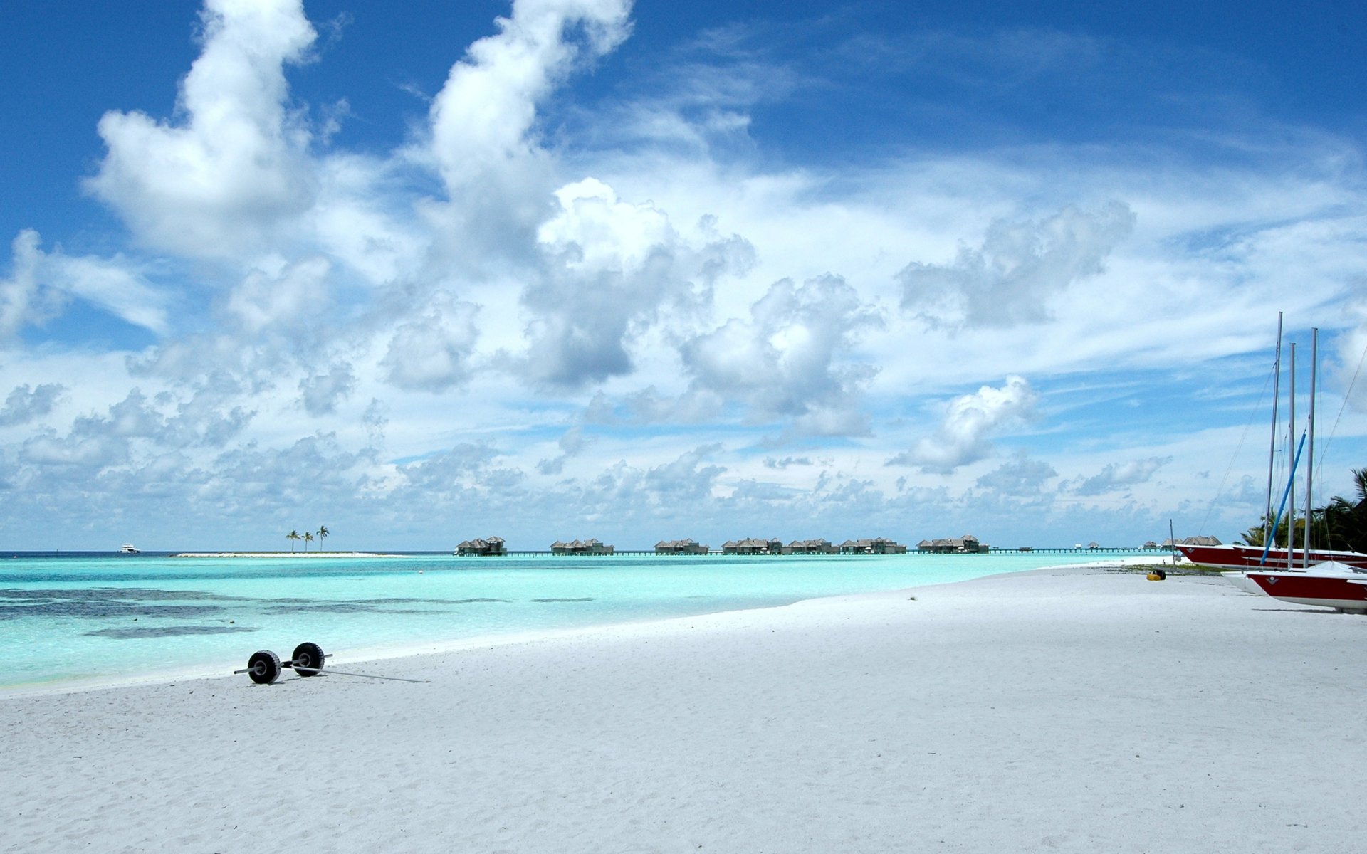 beach sand ocean sky clouds bungalow boat