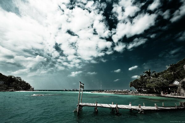 A bridge on the beach by the sea under the sky in the clouds