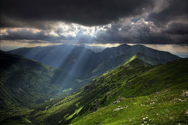 I raggi del sole si infrangono attraverso le nuvole e illuminano le montagne