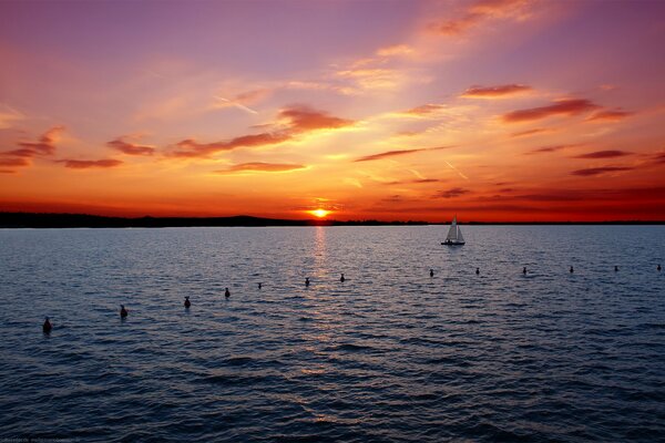 Yacht en mer sur fond de coucher de soleil rouge