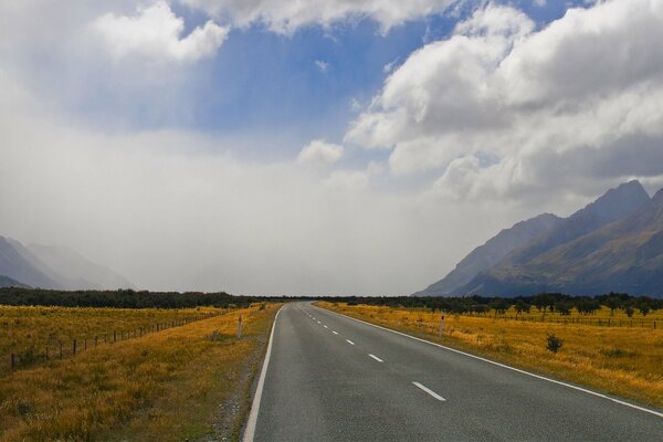 A deserted highway stretching into the horizon among sparse fields