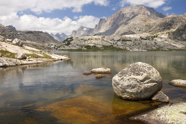 Rocks on a mountain river against a cloudy sky and mountains