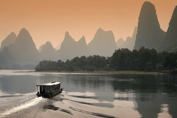 Un barco navega al atardecer por el río