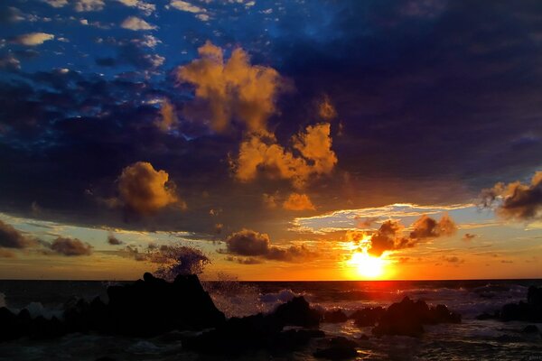 Beautiful sunset among clouds over the rocky coast of the sea