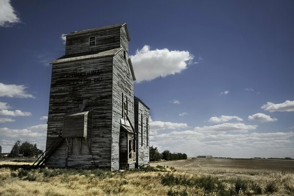 Scheune im Feld. Wolken am blauen Himmel