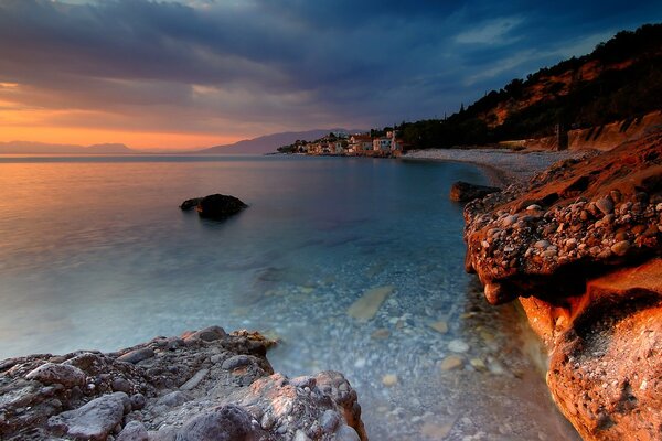 Image of a stone shore near the ocean and a small village