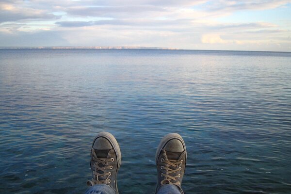 Modische Turnschuhe auf dem Hintergrund des blauen Sees